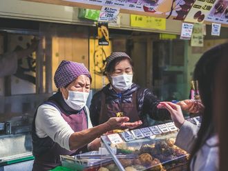 Zwei Japanische Händlerinnen auf einem Marktplatz. Beide tragen Maske