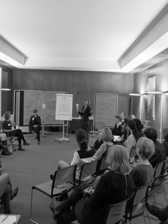 Teilnehmerinnen auf Stühlen während einer Präsentation.