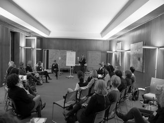 Teilnehmerinnen auf Stühlen während einer Präsentation.