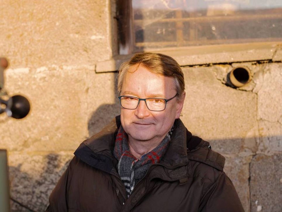 Reiner Brunsch vor einer sonnenbeschienenen Mauer.