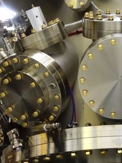 Eine Moleklarstrahlepitaxieanlage mit vielen runden Scheiben aus glänzendem Metall.