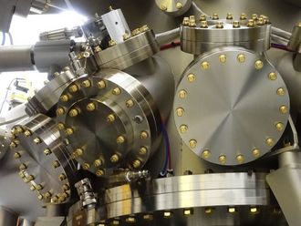 Eine Moleklarstrahlepitaxieanlage mit vielen runden Scheiben aus glänzendem Metall.