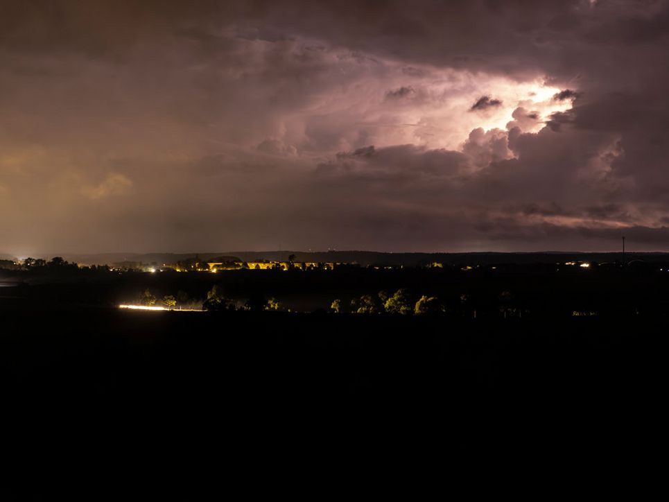 Blick vom Aussichtsturm über den Naturpark Nossentiner/Schwinzer Heide in die Ferne und Dunkelheit. Am Himmel sind Gewitterwolken zu sehen. 