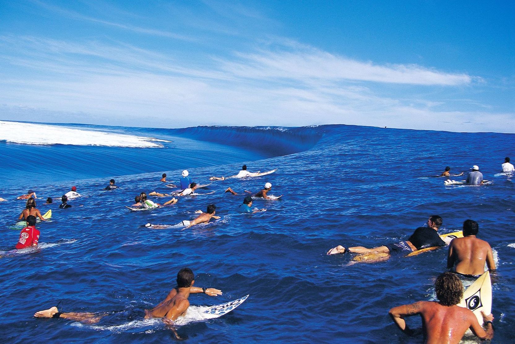 Surfende, auf ihren Brettern liegend, schwimmen auf einer großen Welle.