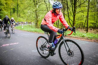 Rennradfahrerin im Wald, hinter ihr einen ganze Kolonne.
