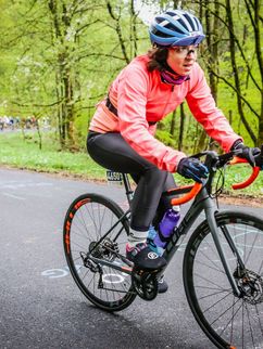 Rennradfahrerin im Wald, hinter ihr einen ganze Kolonne.