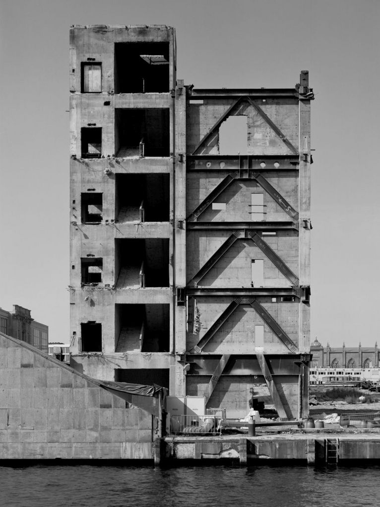 Gebäude am Wasser in städtischer Umgebung, dessen Abriss schon begonnen hat.