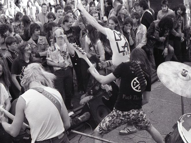 Eine Heavy-Metal-Band spielt ekstatisch vor Publikum auf einer Bühne.