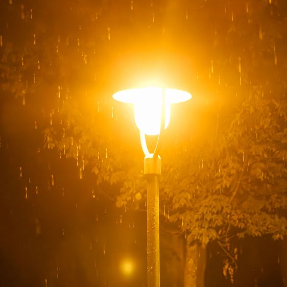 Straßenlaterne in der Nacht leuchtet. Es regnet.