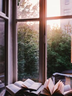 Aufgeschlagene Bücher an einem offenen Fenster.