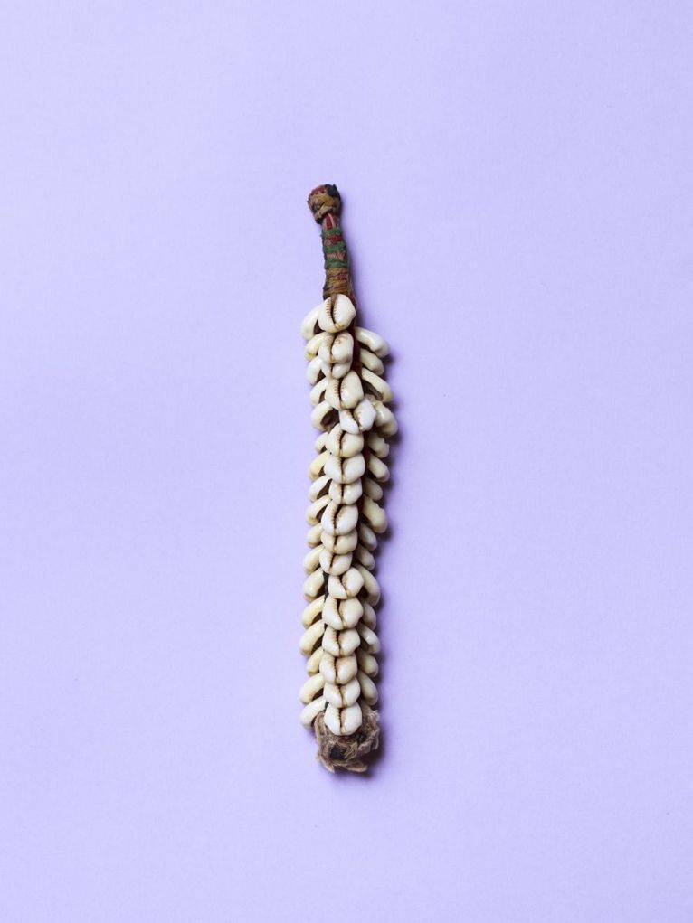 Holzstange mit kleinen weißen Muscheln daran.