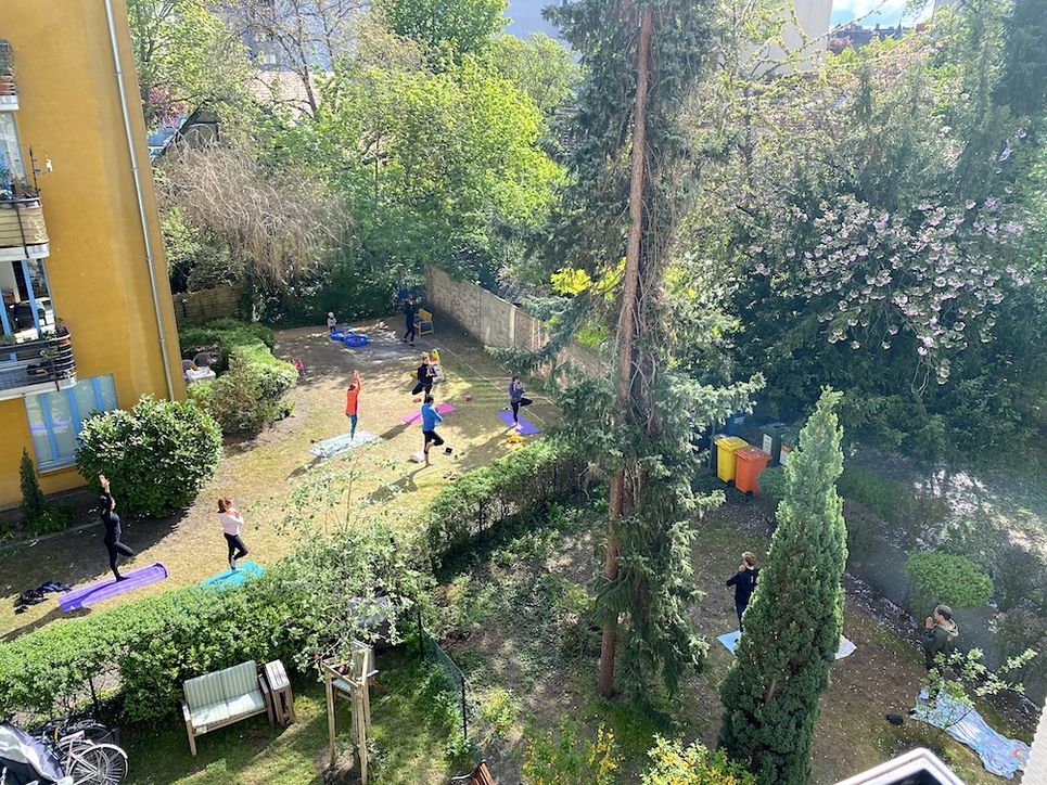 Blick in den sonnigen Innenhof, wo viele Leute Yoga machen.