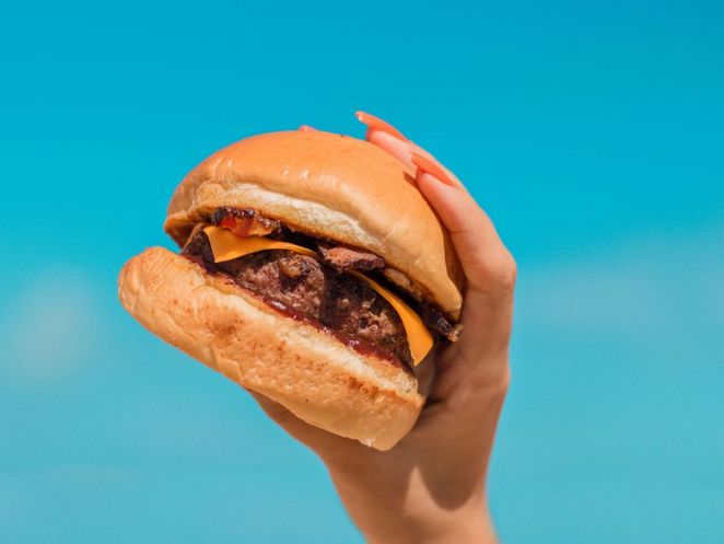 Hand, die einen Veggie-Cheeseburger hält.
