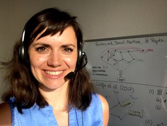 Lydia Recke mit Headset vor einem beschriebenen Whiteboard.