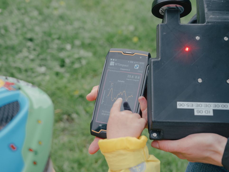 Liina Tõnissons kleine Tochter zeigt auf das Smartphone-Display.