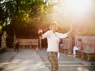 Nisren Habib in einem sonnigen Park mit alten Steinbänken.
