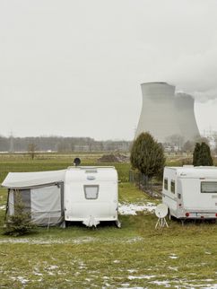 Zwei Wohnwägen auf einer Wiese, im Hintergrund ein Atomkraftwerk.