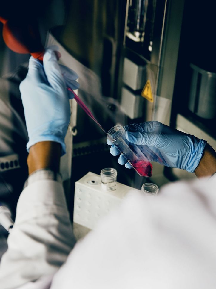 Mit einer Pipette wird rötliche Flüssigkeit in ein Reagenzglas gefüllt.