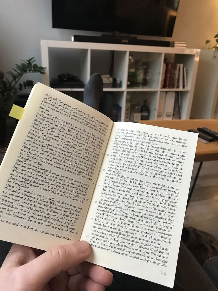 Aufgeschlagenes Buch, das mit einer Hand gehalten wird.