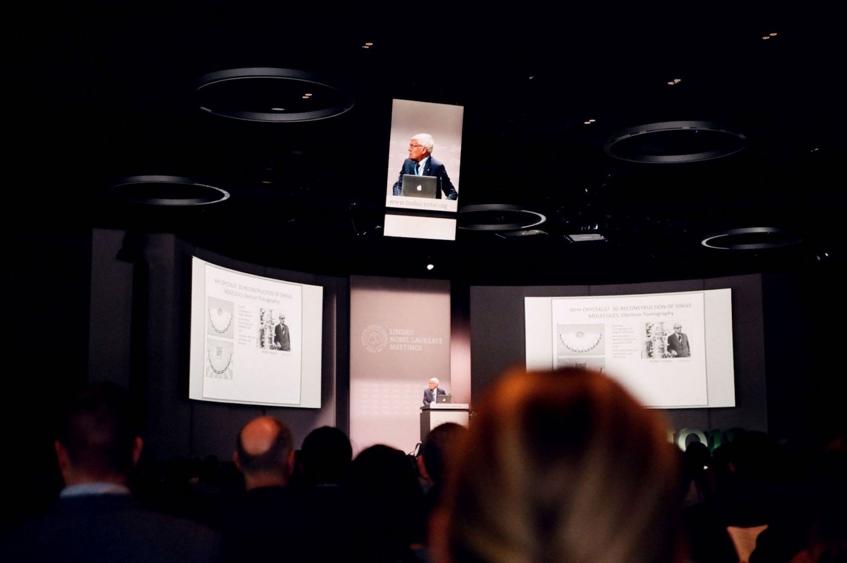 Vortrag mit PowerPoint-Präsentation und Übertragung des Vortragenden auf einem Bildschirm.