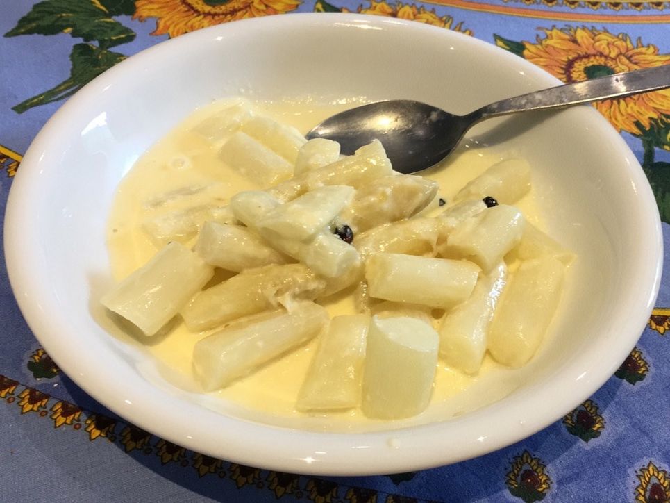 Spargel in Sauce Holondaise in einem Suppenteller mit Löffel.