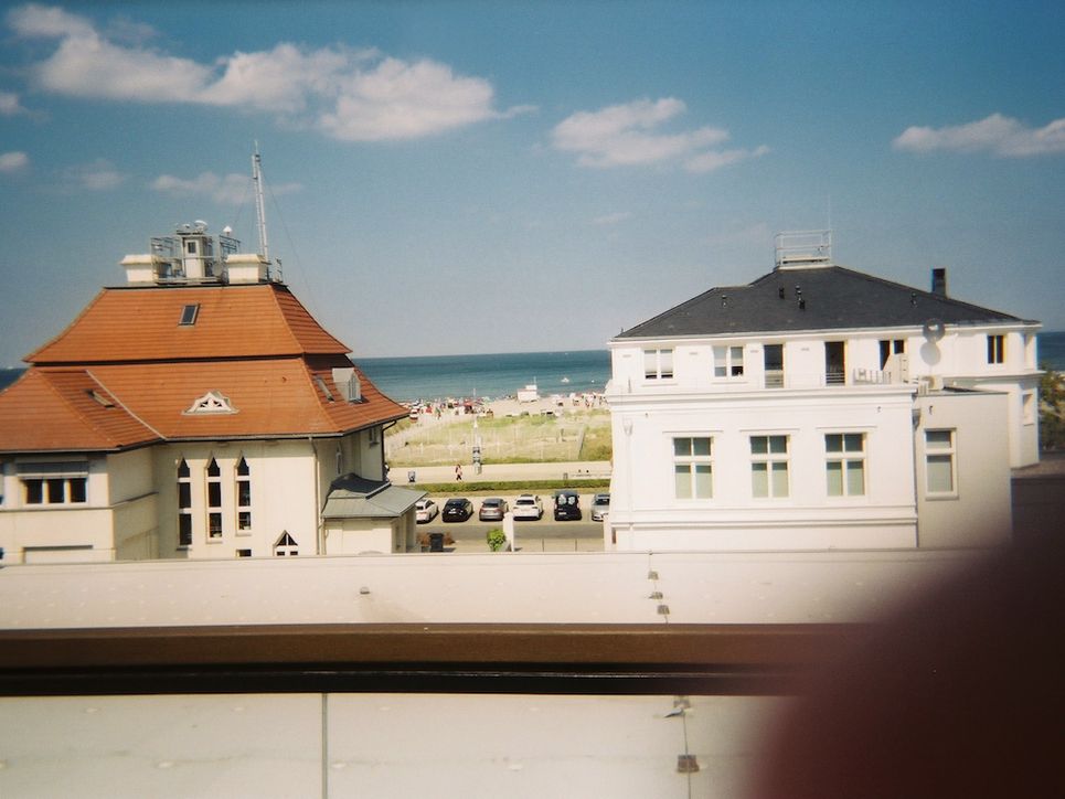 Blick auf weiße Gebäude, dahinter der Strand.