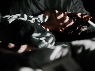 Eine Frau liegt erschöpft in einem abgedunkelten Raum.