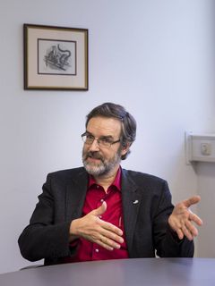 Stefan Treue an einem Tisch sitzend und mit den Händen gestikulierend.