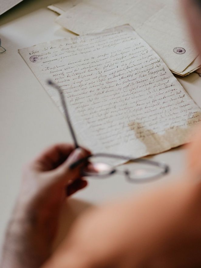 Hand hält eine Brille über einem alten Schriftstück
