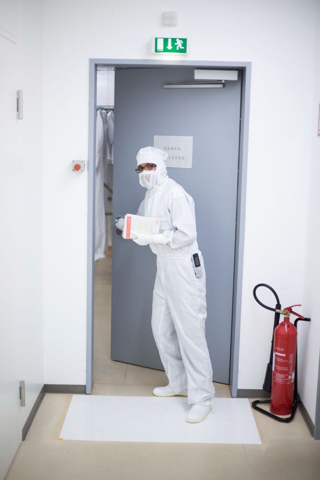 Forscherin in Schutzkleidung geht durch eine Tür mit der Aufschrift: Damenschleuse.
