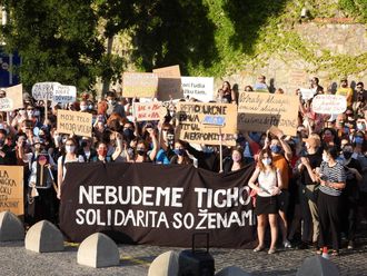 Women during a demonstration, holding up posters and a banner in front