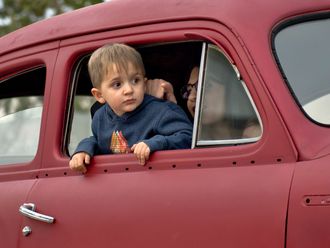 Junge am Fenster eines roten Autos.