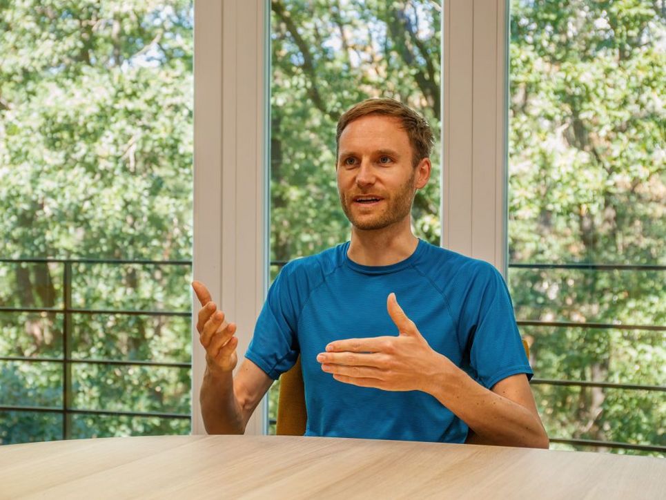 Florian Humpenöder ist dabei, etwas zu erklären, er sitzt an einem Tisch.