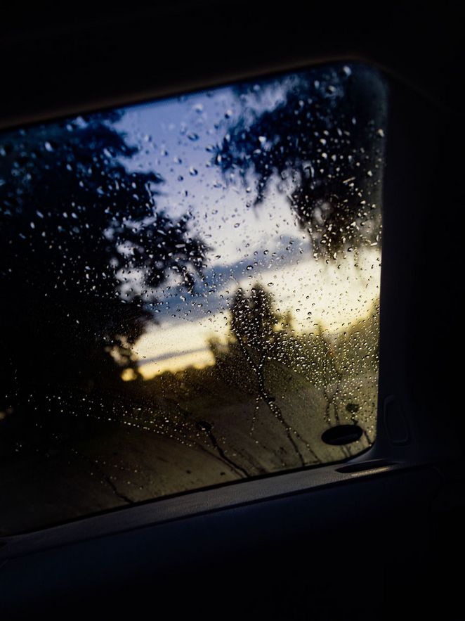 Der Blick aus einem Autofenster, an dem Regentropfen hängen.