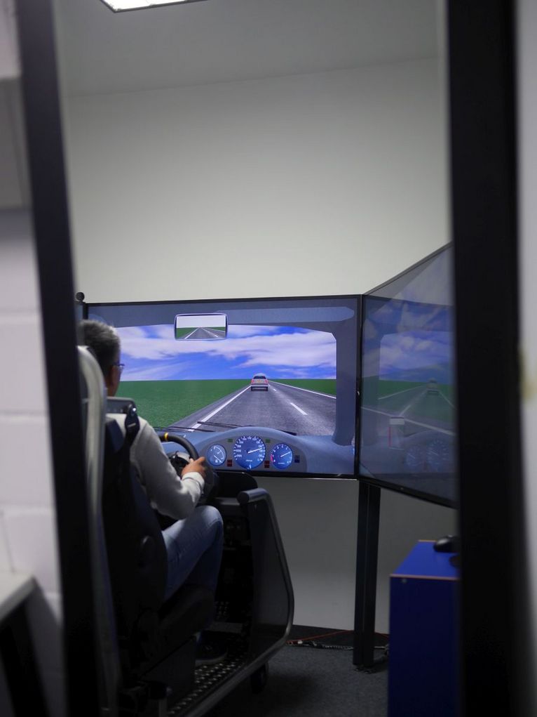 Raum, in dem eine Person einen Fahrsimulator benutzt.