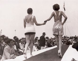 Miss Europa und Miss Amerika laufen 1929 gemeinsam als Miss Universe über einen Laufsteg im Freien. 