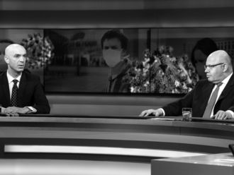 Jonas Schmidt-Chanasit und Peter Altmaier vor einem Fotobanner das unter zwei Personen mit Mund-Nasen-Schutz zeigt.
