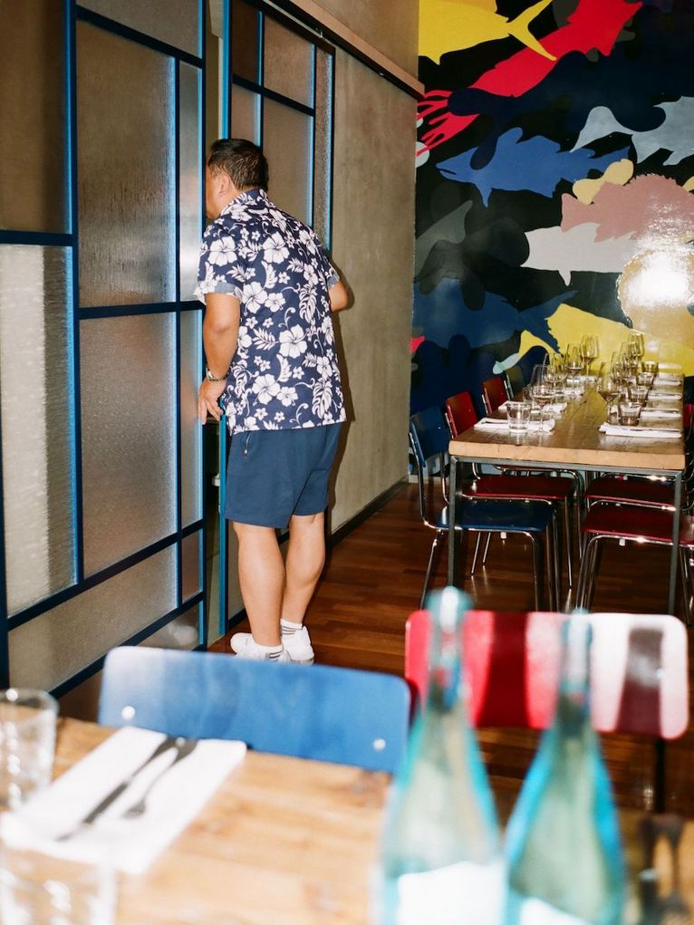 Gedeckte Tische im Restaurant, der Koch schaut zur Tür hinaus.