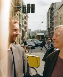 David Schelp und Henriette Löwisch im Gespräch vor einer belebten Straßenkreuzung.