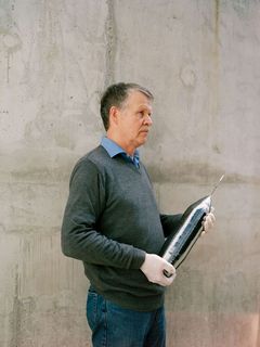 Nikolay V. Abromisov mit einem spitz zulaufenden glatten, grau-glänzenden Kristall.