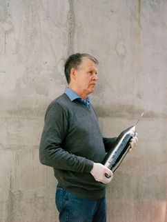 Nikolay V. Abromisov mit einem spitz zulaufenden glatten, grau-glänzenden Kristall.