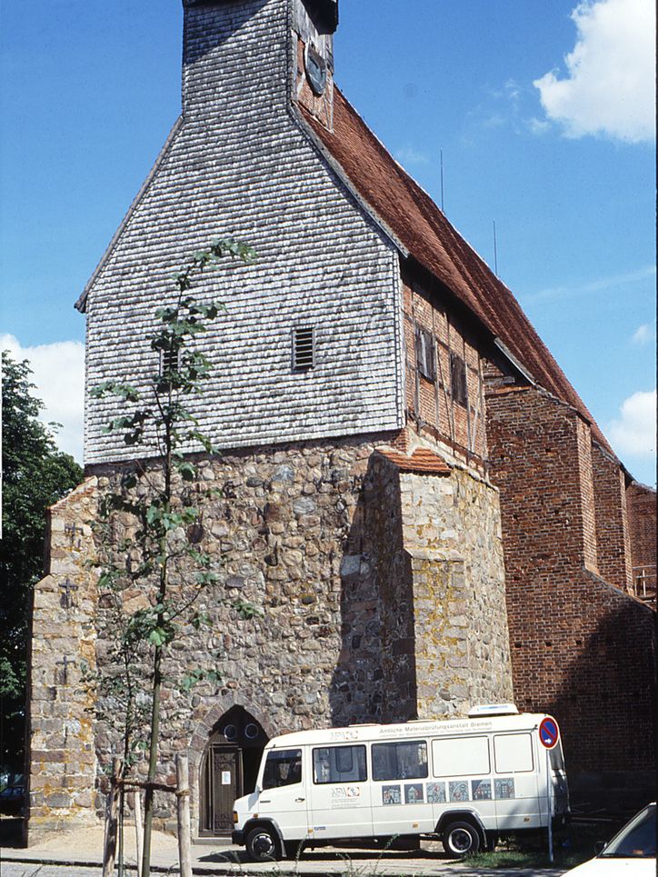 Das Labormobil steht vor einer Kirche in der Sonne.