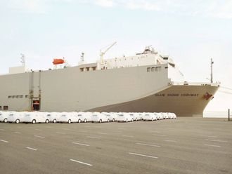Ein riesiges Frachtschiff mit der Aufschrift "Blue Ridge Highway" und viele weiße Autos im Hafengelände.