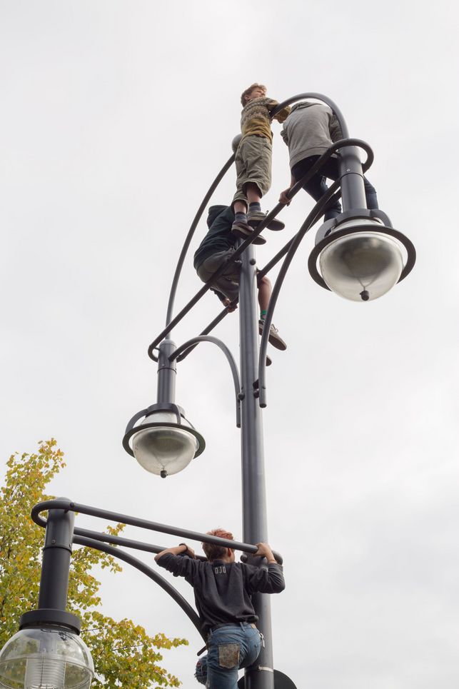 Kinder klettern auf eine Straßenlaterne.