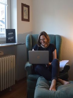 Louise Rokohl in einem Sessel mit Laptop.