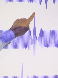 Ein Finger zeigt auf den höchsten Punkt des Graphen einer Lichtwelle.