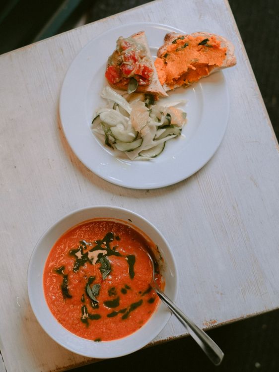 Ein Teller mit Tomatensuppe, ein anderer mit belegten Broten und Gemüse.