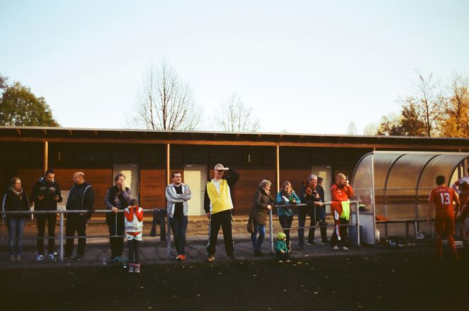 Personen am Rand eines Fußballfeldes.