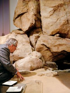 Wolfgang Böhme kniet vor einer steinernen Höhle