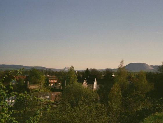 Blick auf Häuser und Schienen im Grünen.